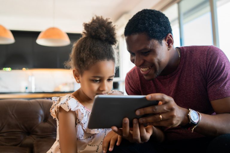 A young girl and her father using a tablet at home