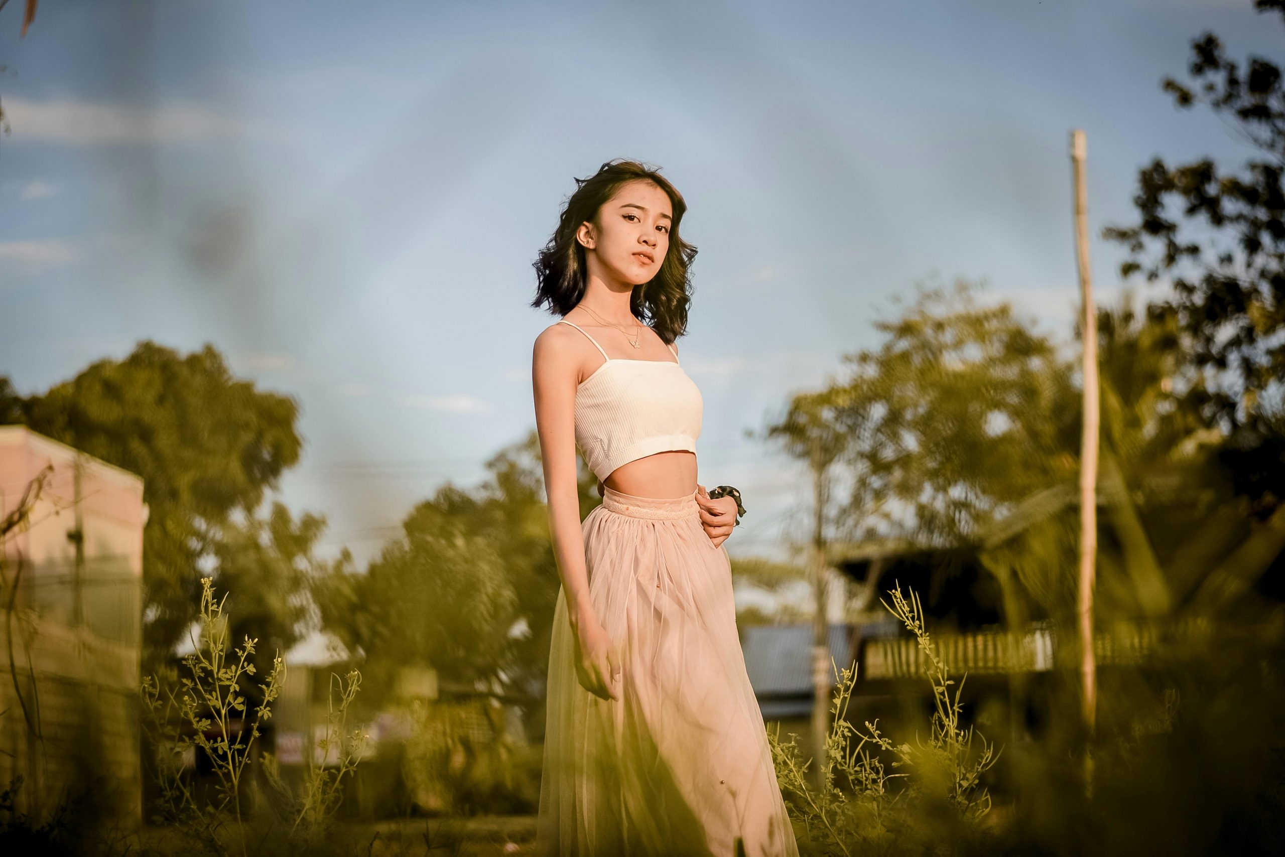 petite woman wearing a pink maxi skirt and a white cropped top